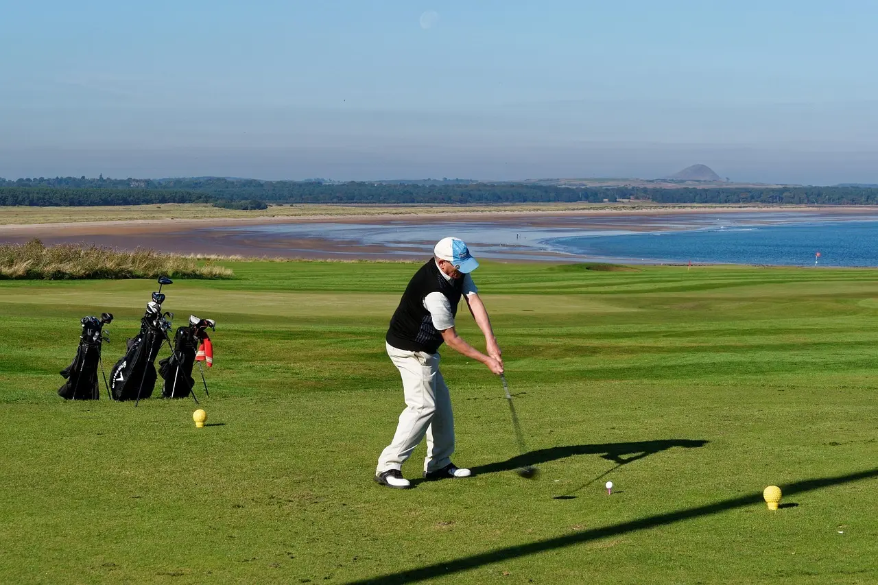 Golfspiller der slår et slag på en kystnær golfbane