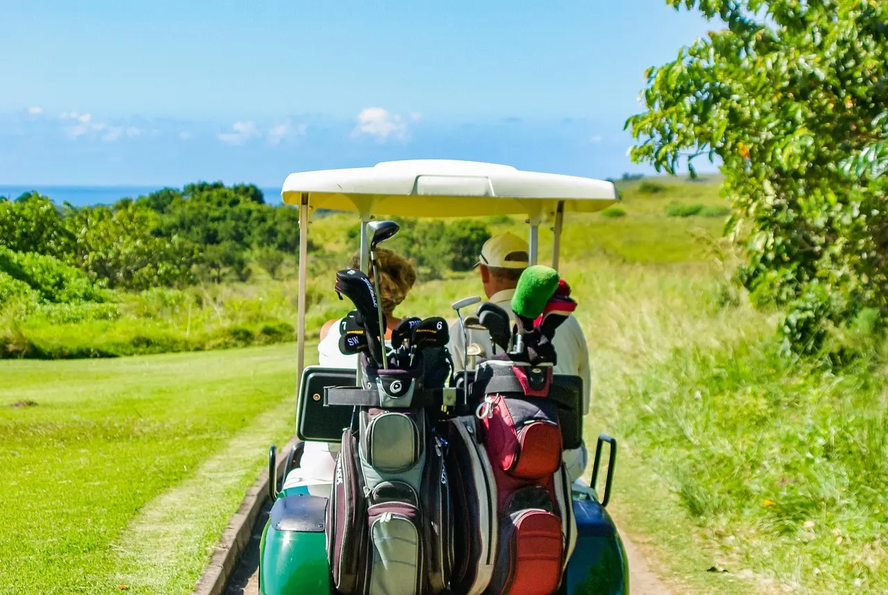 Golfvogn med to personer på en grøn golfbane